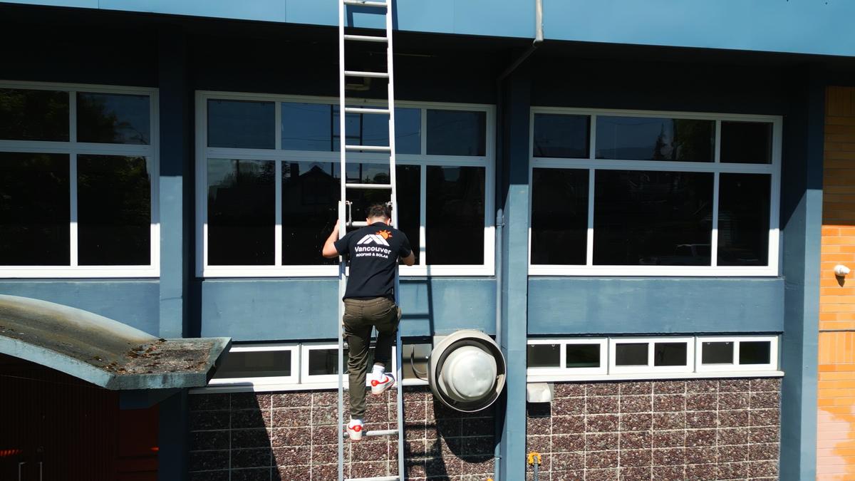 A Vancouver Roofing & Solar crew member climbing a ladder on site