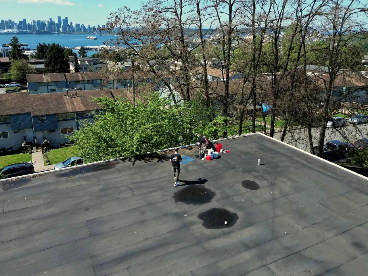 Vancouver Roofing & Solar crew working a flat roof with the downtown Vancouver skyline in the background
